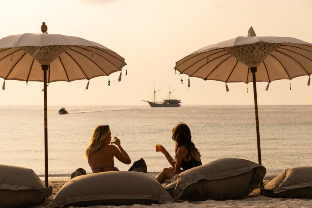 Relaxing on the beach at sunset with cocktails on a private cruise with Prana by Atzaro in Raja Ampat